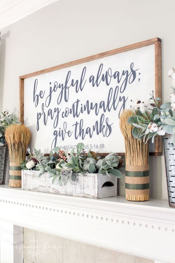 a stylish modern farmhouse mantel with wheat arrangements, a large sign, a whitewashed box with pale greenery and berries