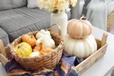 a tray with a checked napkin, a basket with faux gourds and pumpkins, a stack of pumpkins and a white vase with fall blooms