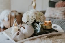 a tray with a stack fo books, a candle, white fabric pumpkins and a white rose arrangement for a touch of glam