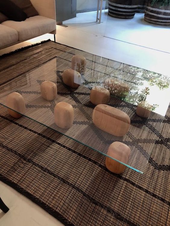 a unique coffee table of wooden pieces and a glass tabletop placed on them looks very zen-like and creative