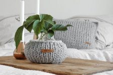 a vase covered with a grey chunky cozy and a matching pillow case are a great solution to style your space for the fall or winter