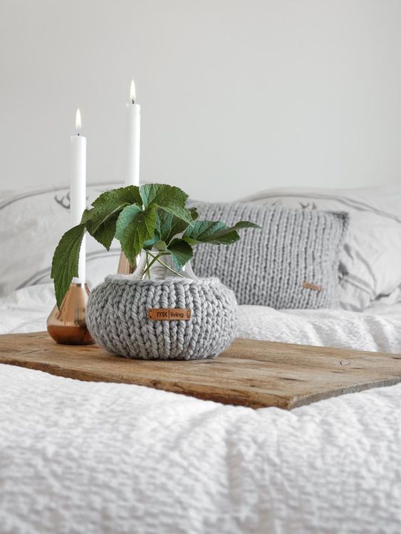 a vase covered with a grey chunky cozy and a matching pillow case are a great solution to style your space for the fall or winter