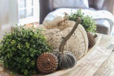 a wooden bowl with greenery balls, fabric pumpkins, fake acorns for a cool and bold famrhouse-inspired look