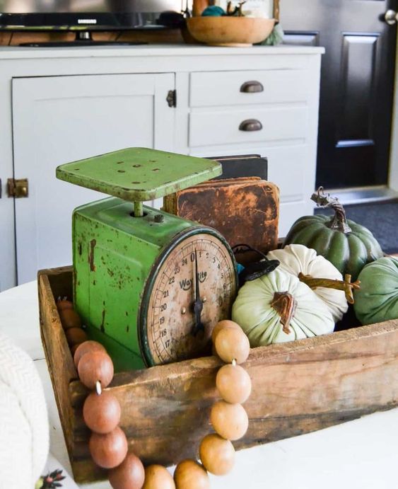 a wooden box with wooden beads, natural and fabric pumpkins and vintage scales for a rustic space