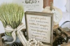 a wooden tray with beads, pinecones, wheat in a small bucket, fabric pumpkins and a sign for cozy fall decor