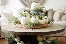 a woven tray with greenery and white pumpkins plus a bucket for cozy rustic fall decor