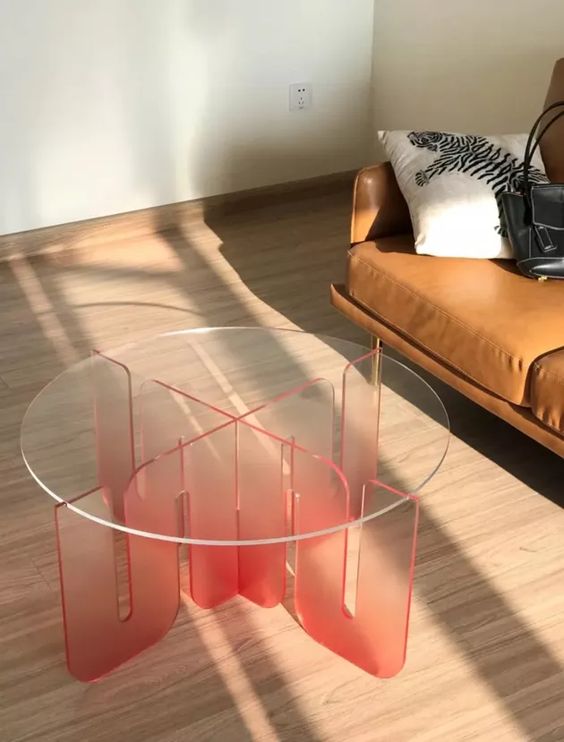 an acrylic coffee table of a semi-sheer red acrylic base and a clear glass tabletop is a bold and fun touch to the space