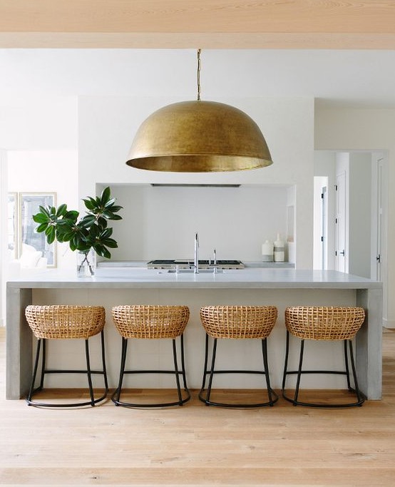 an oversized metal pendant lamp echoes with the rattan chairs and brings texture to the kitchen