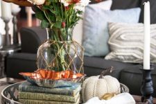 fabric pumpkins, a clear vase with rust and white blooms and a stack of books for fall decor