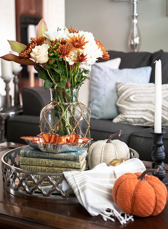 fabric pumpkins, a clear vase with rust and white blooms and a stack of books for fall decor