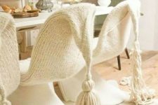 plastic chairs covered with neutral knit covers with tassels look very cozy and unusual and give a welcoming feel to the space