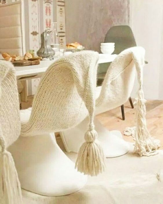 plastic chairs covered with neutral knit covers with tassels look very cozy and unusual and give a welcoming feel to the space
