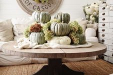 white fabric and large heirloom pumpkins plus green hydrangeas stacked on it for a famrhouse living room