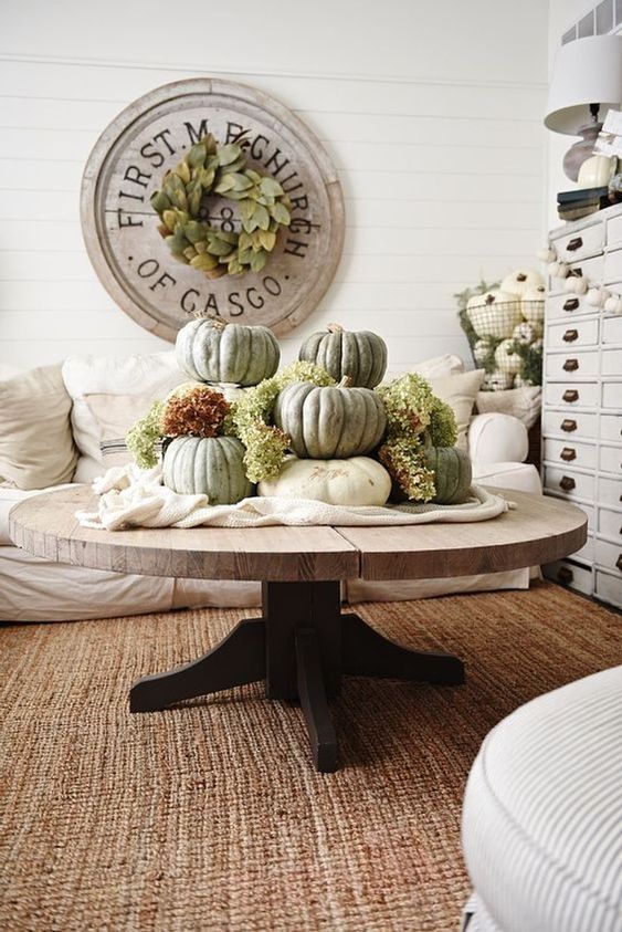 white fabric and large heirloom pumpkins plus green hydrangeas stacked on it for a famrhouse living room