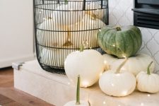 Halloween decor with a wire basket with white and green pumpkins and lights is amazing for minimal and natural Halloween styling
