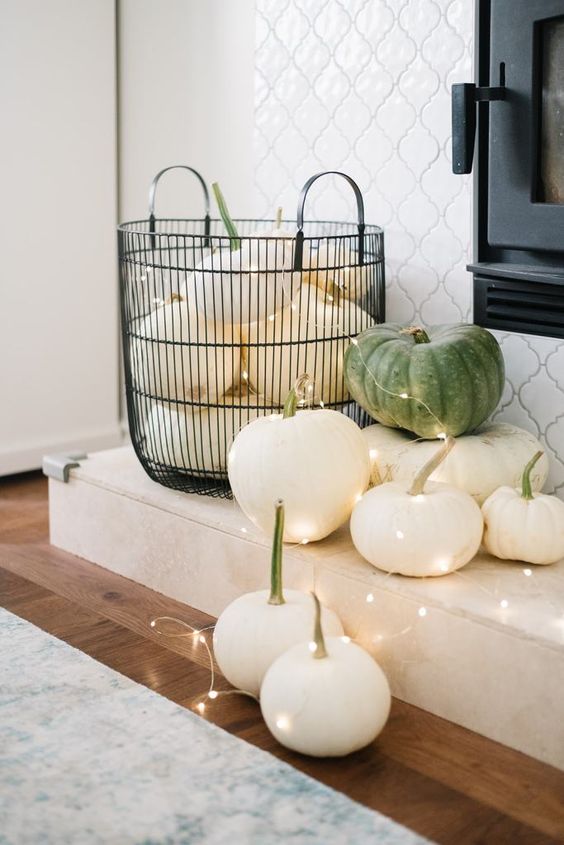 Halloween decor with a wire basket with white and green pumpkins and lights is amazing for minimal and natural Halloween styling