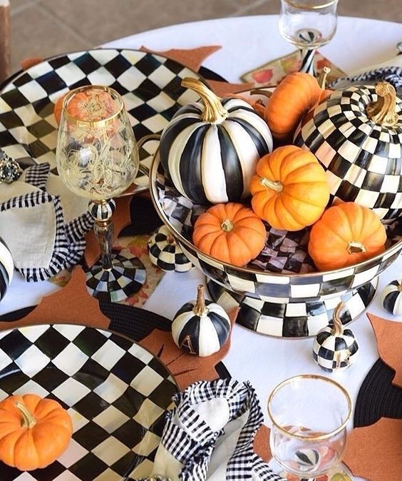 a bold Thanksgiving tablescape done in black and white, with printed pumpkins and checked tableware, spruced up with orange pumpkins