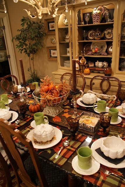 a bold vintage Thanksgiving tablescape with plaid placemats, green mugs, brown candles, a bold pumpkin and dried leaf centerpiece