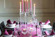 a bright Thanksgiving tablescape with a purple table runner and napkins, purple and pink candles, silver candleholders and purple glasses
