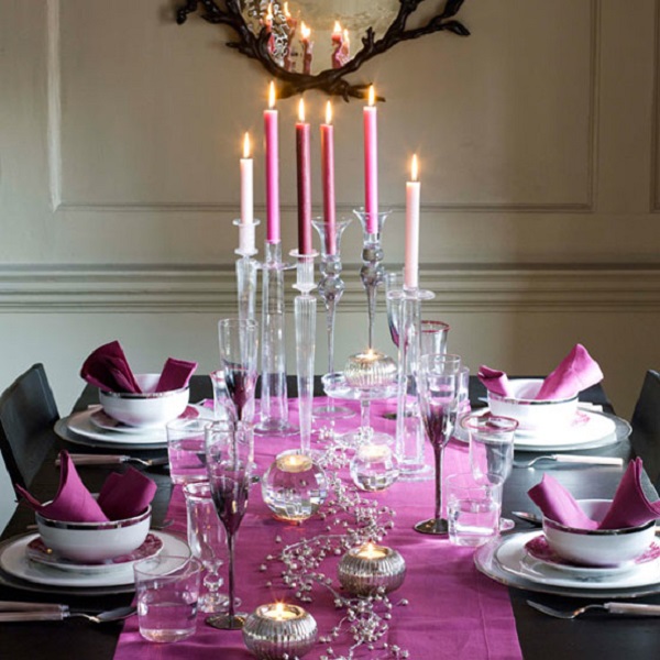 a bright Thanksgiving tablescape with a purple table runner and napkins, purple and pink candles, silver candleholders and purple glasses