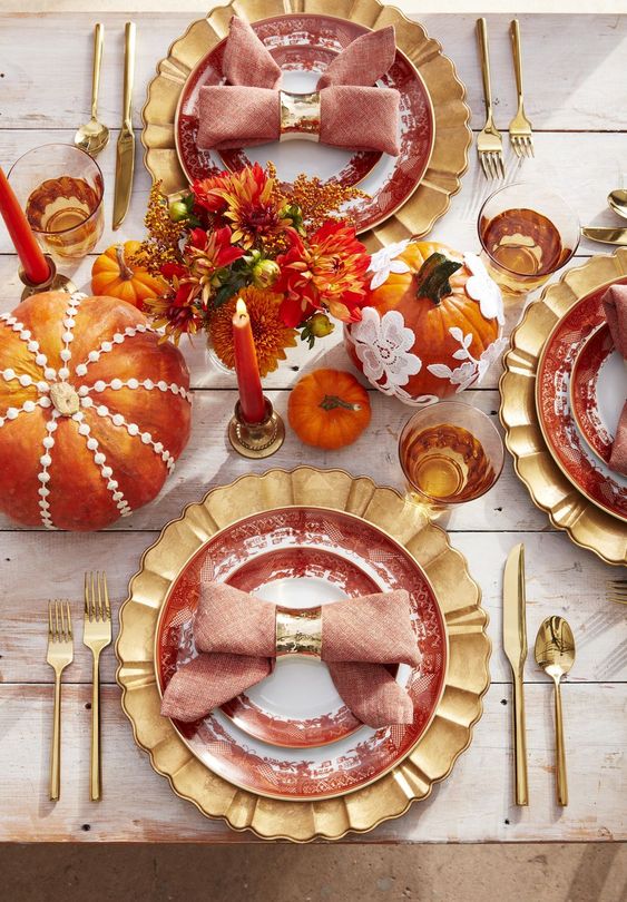 a bright and whisy Thanksgiving tablescape with gold chargers, cutlery, colorful pumpkins and floral arrangements, bold candles