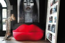 a catchy living room with dark walls, a creative ledge storage unit and ared lip-shaped sofa and a bold artwork