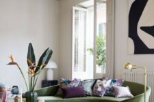 a chic and refined living room done with tiles, a black marble coffee table and a chic green curved sofa as a centerpiece