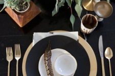 a chic black and white Thanksgiving table setting with a fresh veggie centerpiece, black and white plates, gold and brass touches