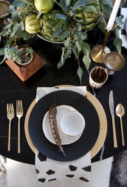 a chic black and white Thanksgiving table setting with a fresh veggie centerpiece, black and white plates, gold and brass touches