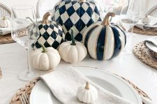 a chic modern farmhouse Thanksgiving tablescape with blakc and white pumpkins, woven placemats, neutral linens and glasses