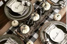 a cozy Thanksgiving tablescape with a buffalo check runner, black and white plates, printed napkins and black and white pumpkins