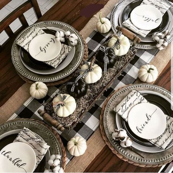 a cozy Thanksgiving tablescape with a buffalo check runner, black and white plates, printed napkins and black and white pumpkins