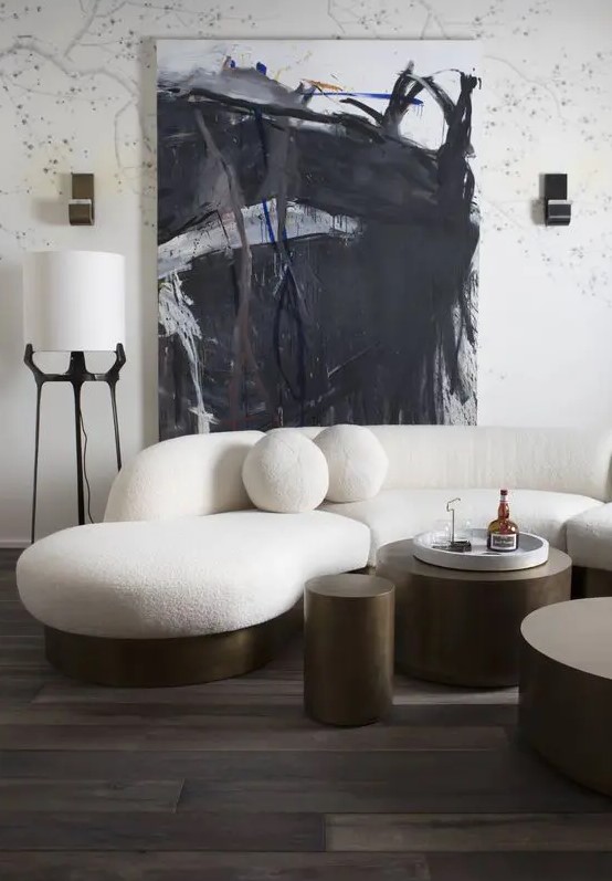 a creamy sculptural rounded sofa with a brass base of metal and round pillows will make a stylish statement in the space