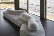 a creative sculptural sofa in grey, composed of some pieces and some cushions on top is a lovely piece inspired by the rocks