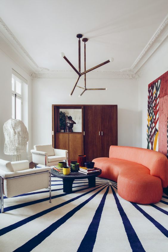 a curved coral sofa makes a statement in this space, with its color and shape, and it perfectly finishes the room off
