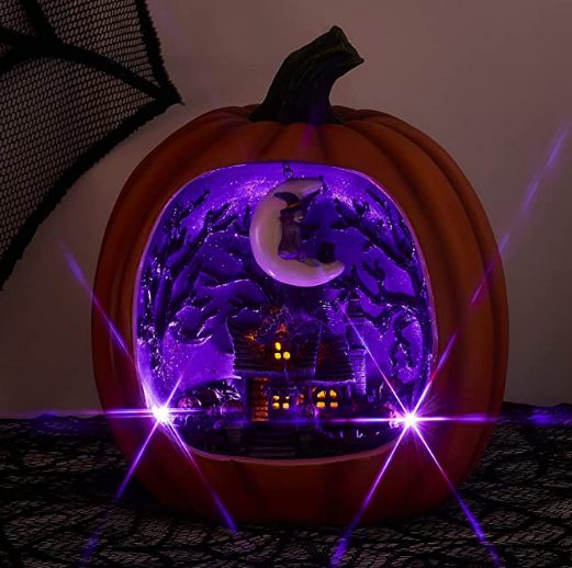 a faux pumpkin with a purple Halloween scene inside - a house with scary trees and a crescent moon with a witch