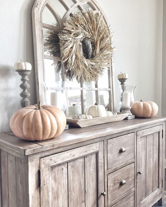 a neutral rustic Thanksgiving console table with a corn husk wreath, large and small pumpkins and candles