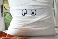 a pillow wrapped with white cheesecloth and with painted eyes as a cute mummy pillow