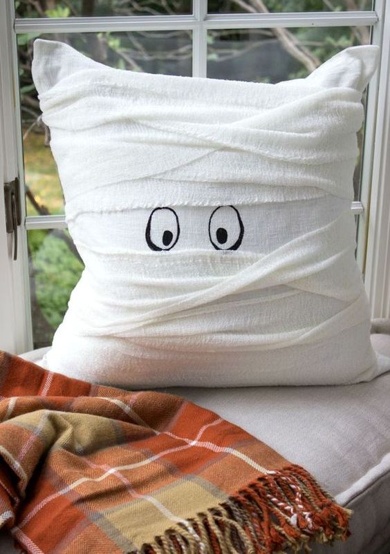 a pillow wrapped with white cheesecloth and with painted eyes as a cute mummy pillow