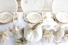 a refined Thanksgiving tablescape with gold chargers, cutlery, white glitter pumpkins and metallic leaves