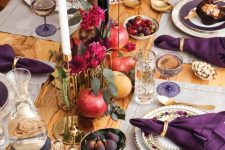 a refined Thanksgiving tablescape with neutral placemats, purple napkins, bold fuchsia blooms, gold touches and berries