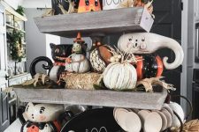 a rustic Halloween stand with hay, pumpkins, husks, vintage toys and fall leaves and other bright stuff