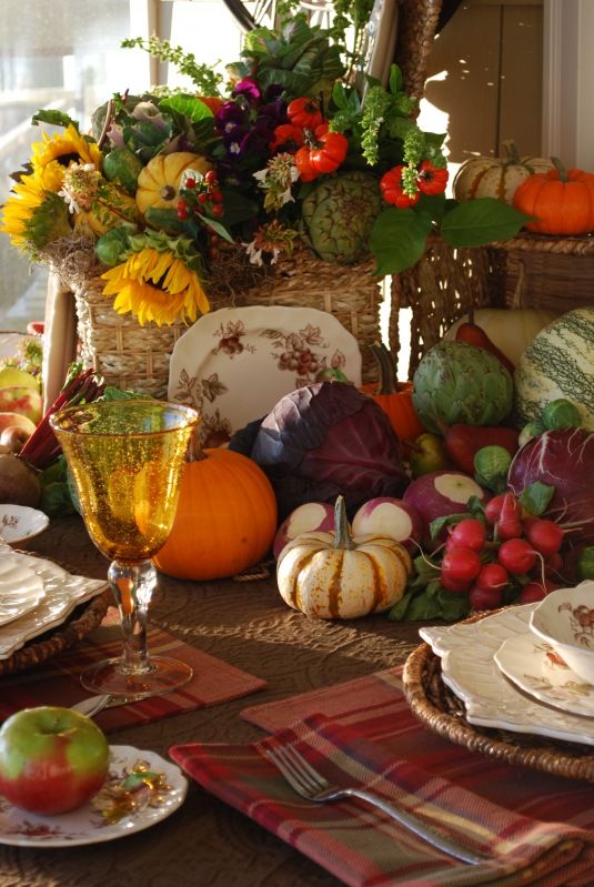 a rustic vintage Thanksgiving tablescape with plaid napkins, a veggie, greenery and bright sunflower centerpiece, colorful glasses