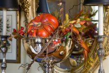 a shiny metallic bowl with faux pumpkins, greenery, berries and twigs for Thanksgiving decor