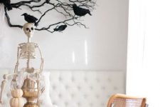 a skeleton on a metallic jar, with a stack of pumpkins, black branches with blackbirds are amazing for Halloween decor