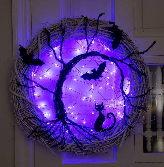 a super bold and catchy Halloween wreath with bats, a black cat and a black tree plus purple lights is an amazing idea to rock