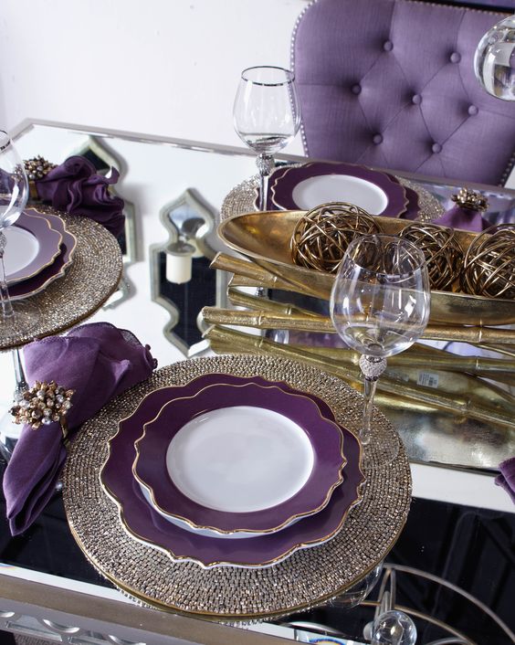 a super glam Thanksgiving tablescape with a mirror table, shiny placemats, a gold bowl with gold yarn balls, purple plates and napkins