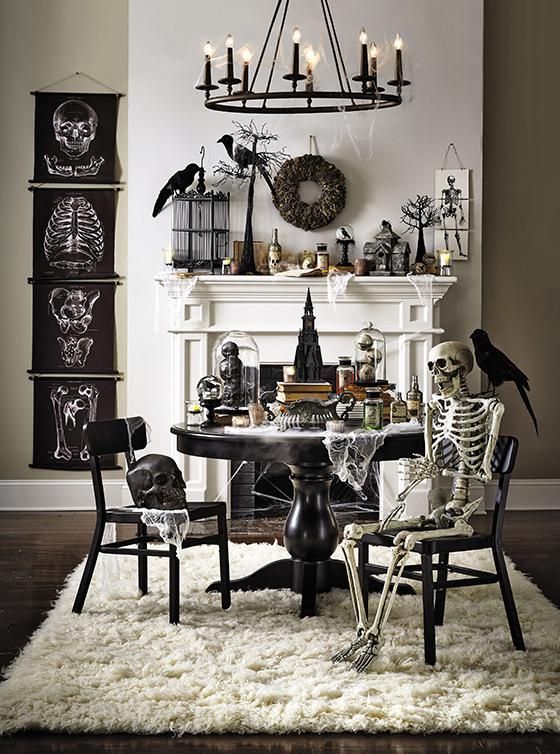 a vintage Halloween space with black posters, skeletons and skulls, blackbirds and wreaths, black furniture and a candle chandelier is wow