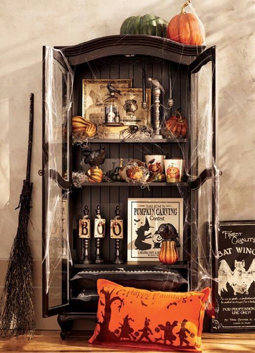 a vintage Halloween storage unit in black, with pumpkins, gourds, candles, signs and a broom by its side is a lovely idea for your party