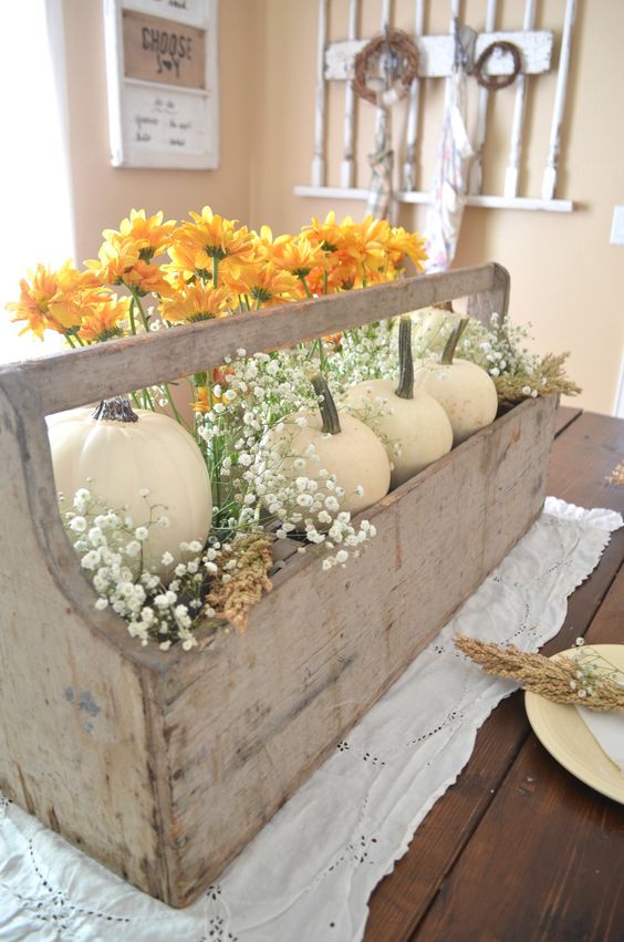 a vintage rustic Thanksgiving centerpiece of a wooden box with white pumpkins, orange blooms and baby's breath